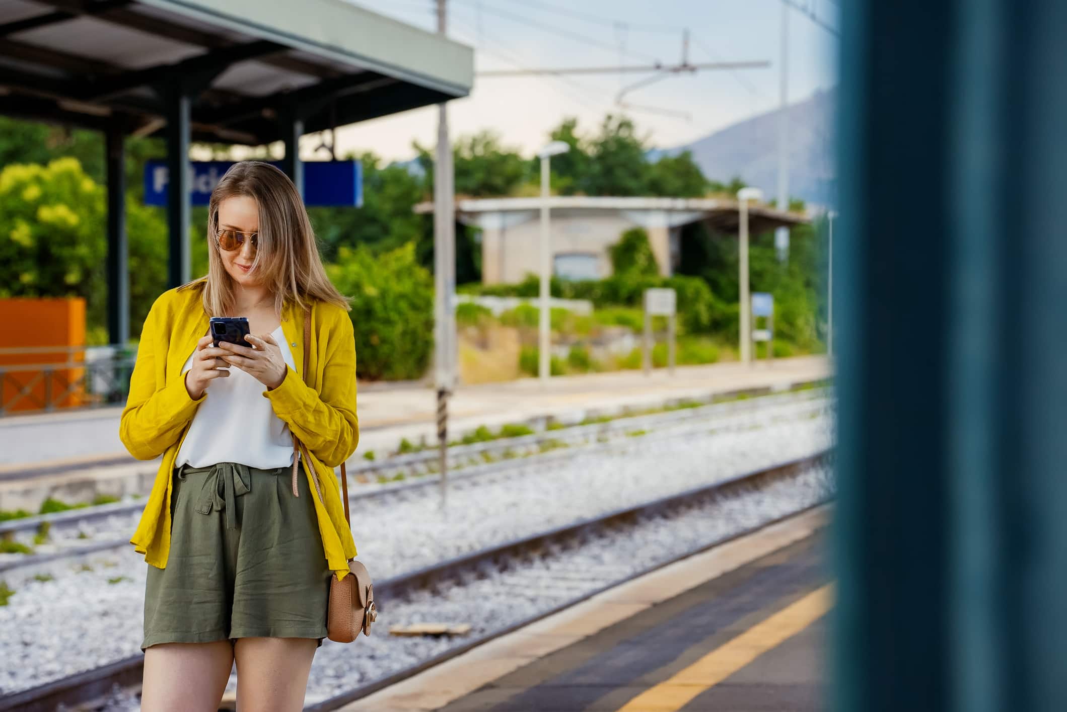Woman With Smartphone Is Waiting For Her Train.